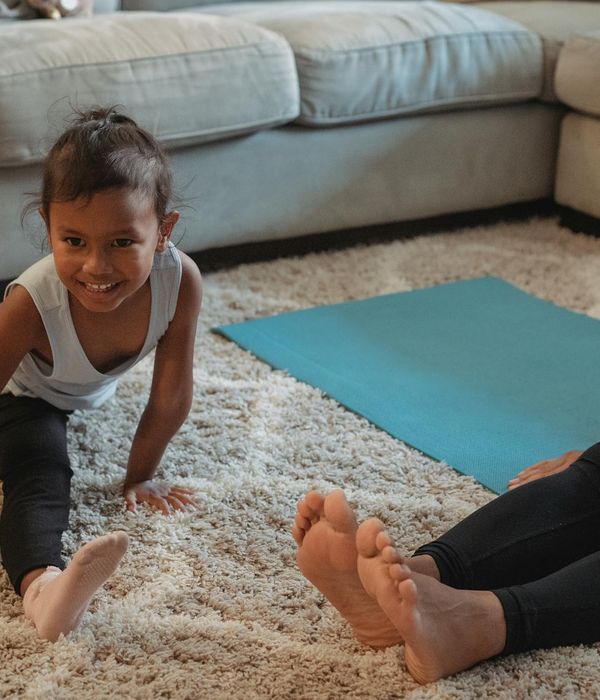 Happy smiling child in a simple yoga pose on a blue mat.